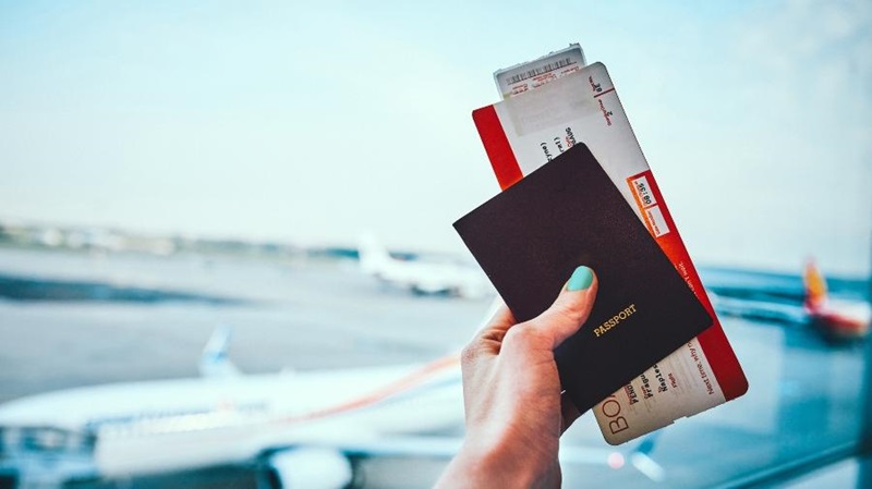 Mulher segurando o passaporte e a passagem aérea